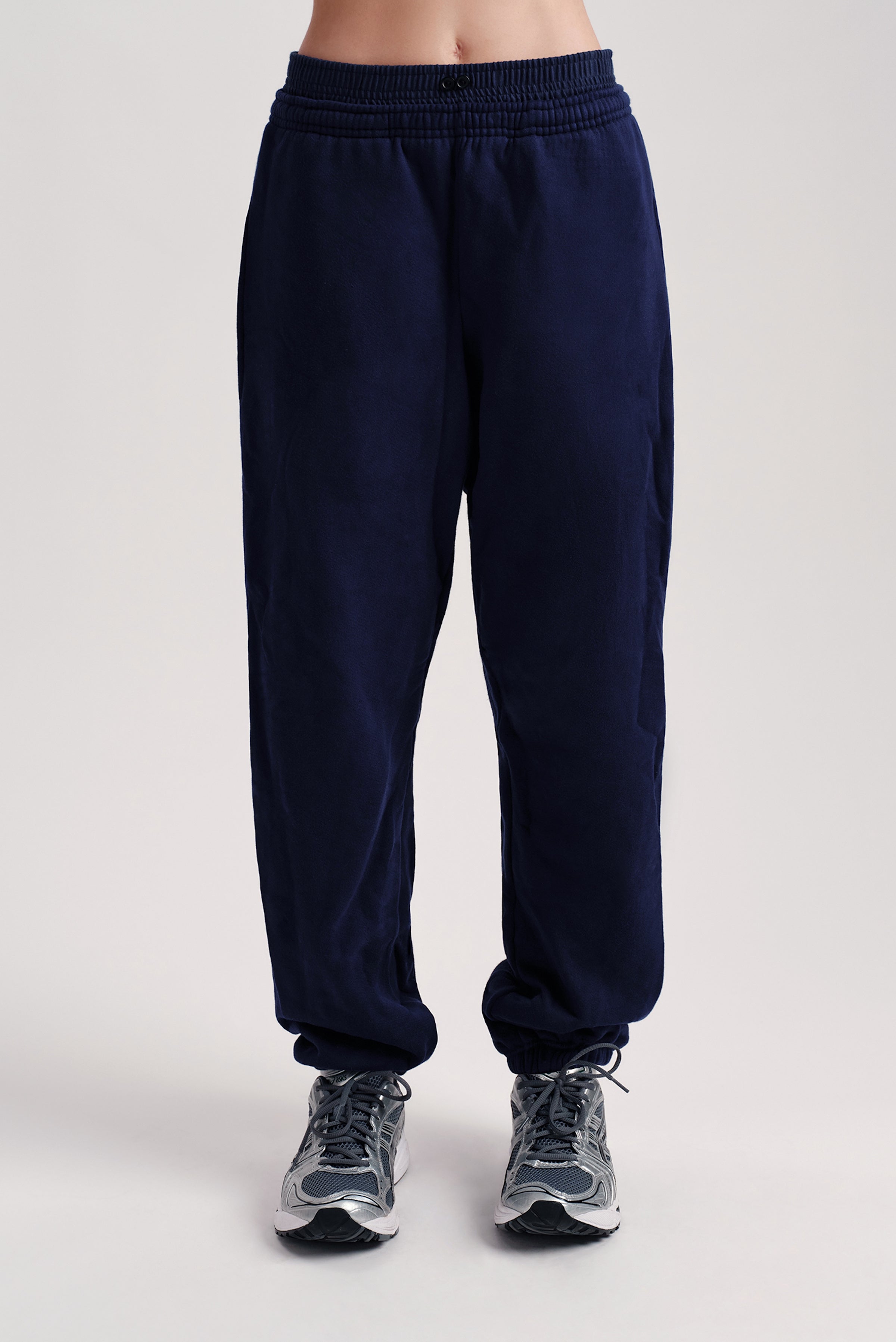 Navy blue sweatpants worn by a person on a light gray background 