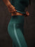 Person wearing teal athletic leggings with a dark background