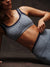 Person wearing a gray sports bra and leggings on a dark background