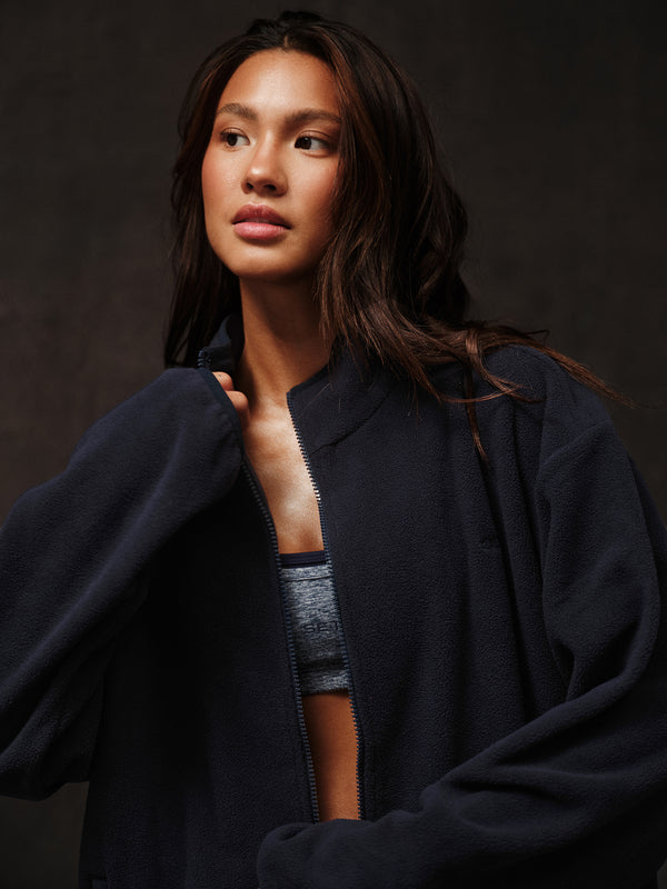 Woman wearing a navy jacket against a black background