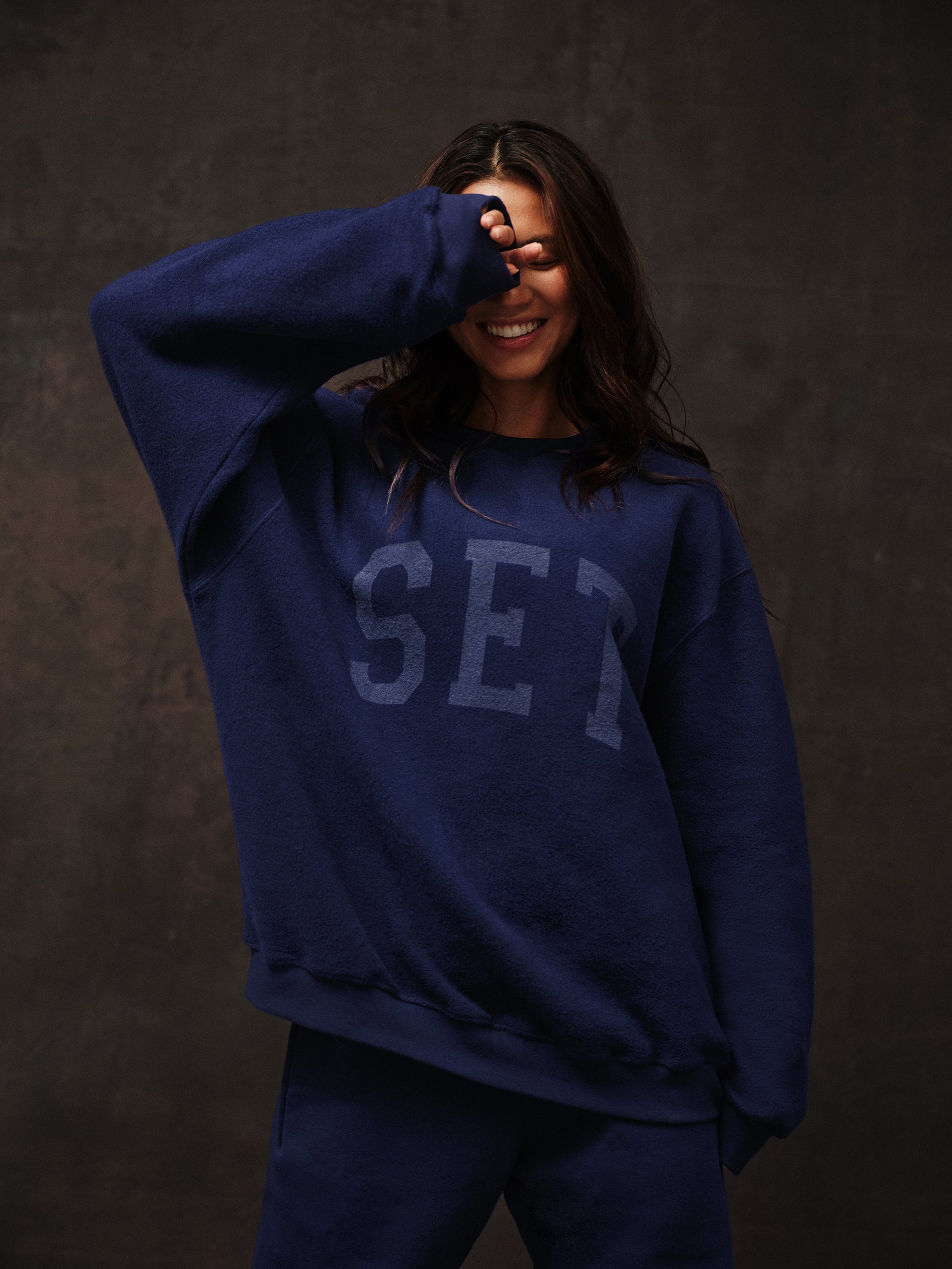 Person wearing a blue sweatshirt with 'SET' text against a dark background