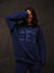 Person wearing a blue sweatshirt with 'SET' text against a dark background