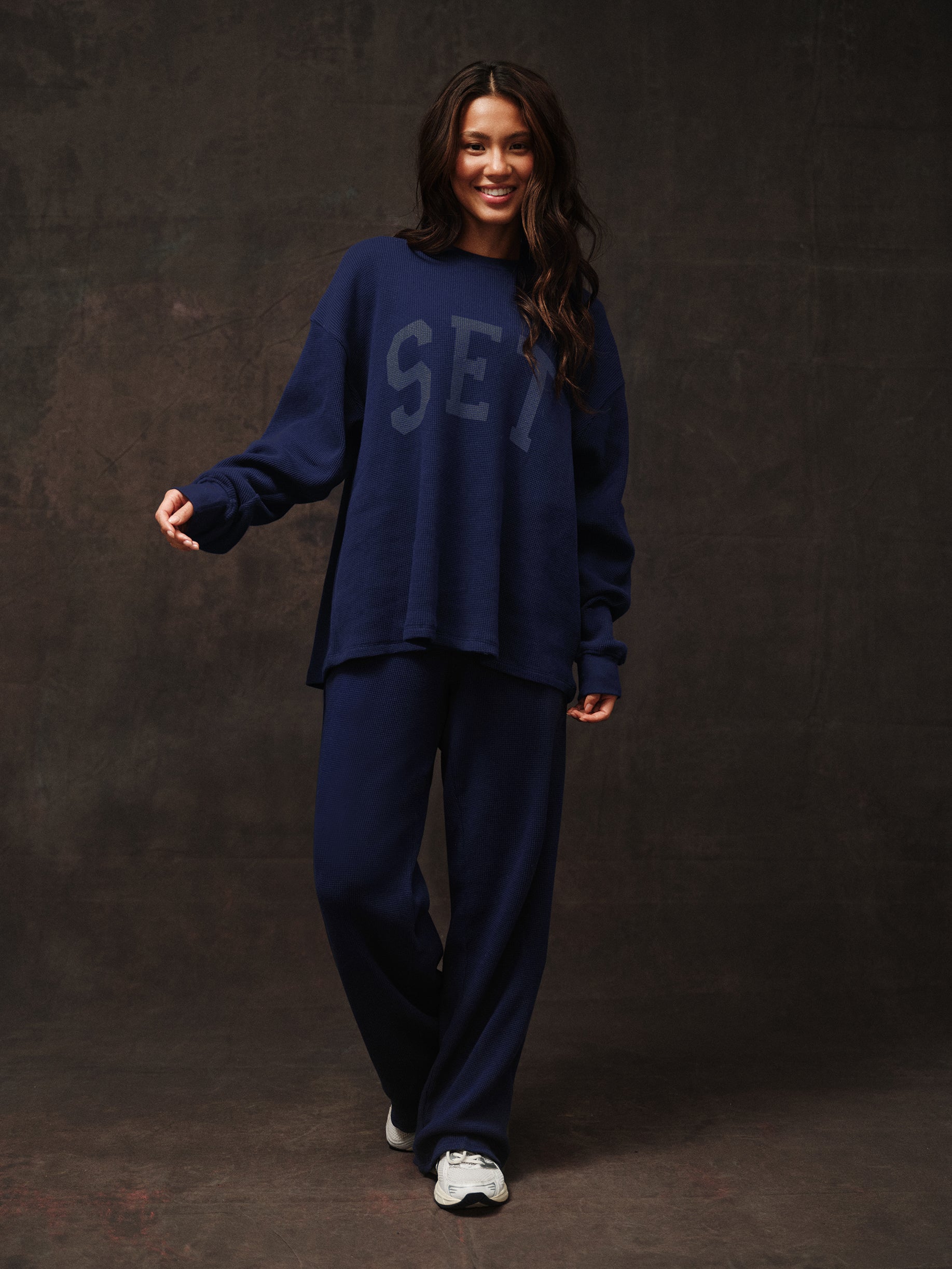 Woman wearing a navy blue outfit with 'SET' text on a dark background