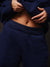 Person wearing a navy blue tracksuit against a dark background
