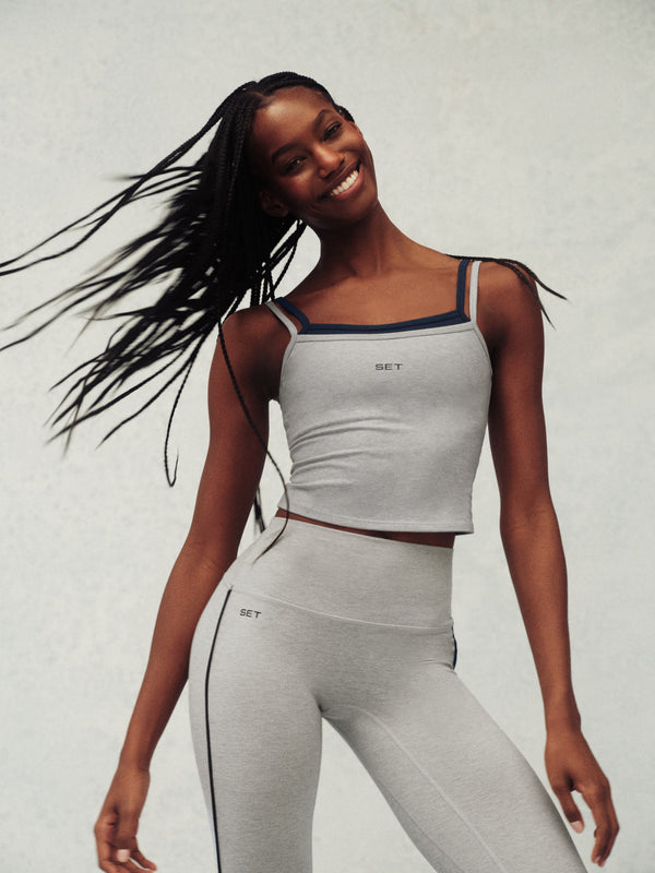 Woman wearing a gray athletic outfit with a white background
