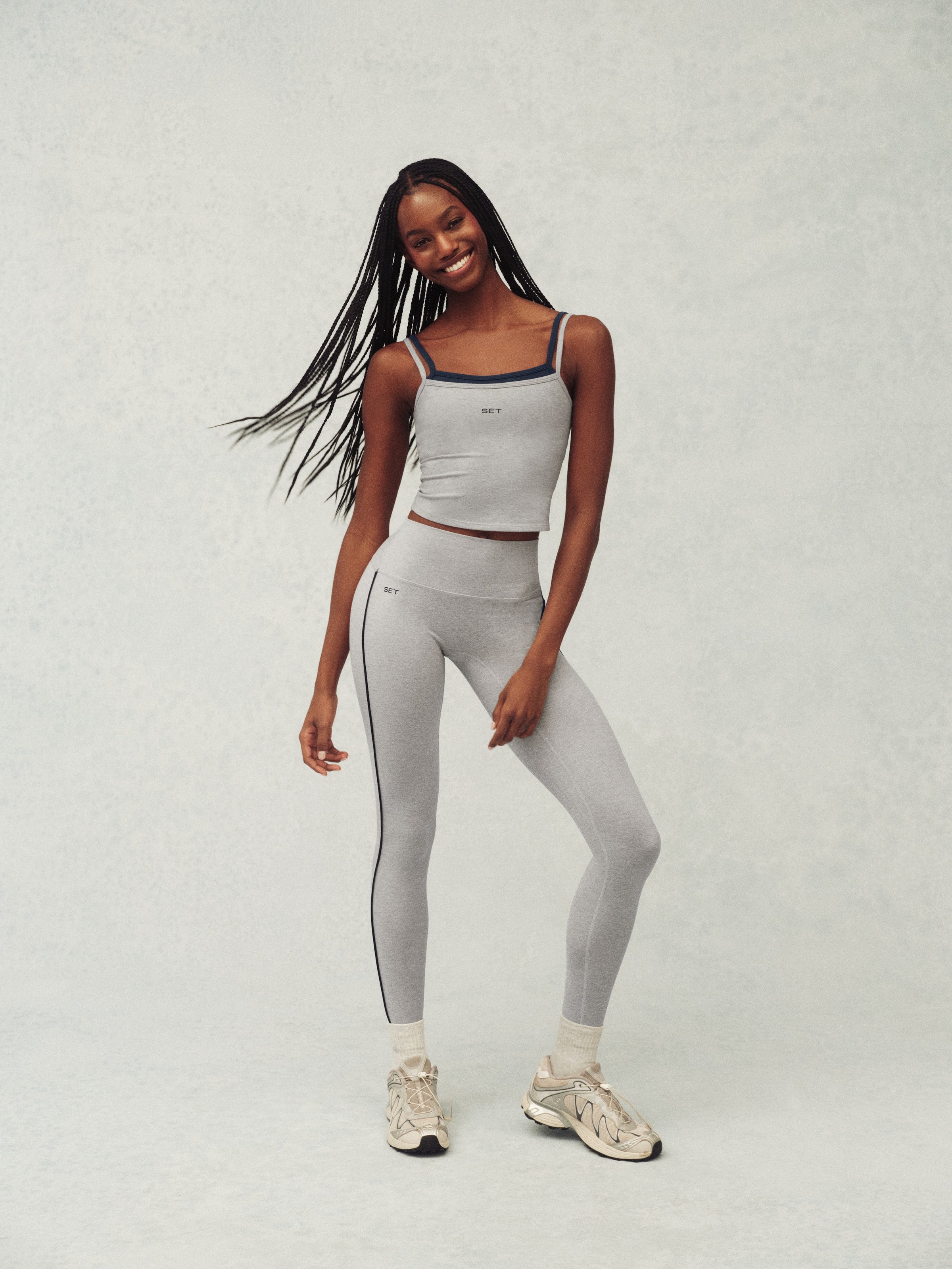 Woman wearing a gray athletic outfit on a white background