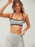 Woman wearing a gray sports bra and leggings with a visible brand logo on a plain background