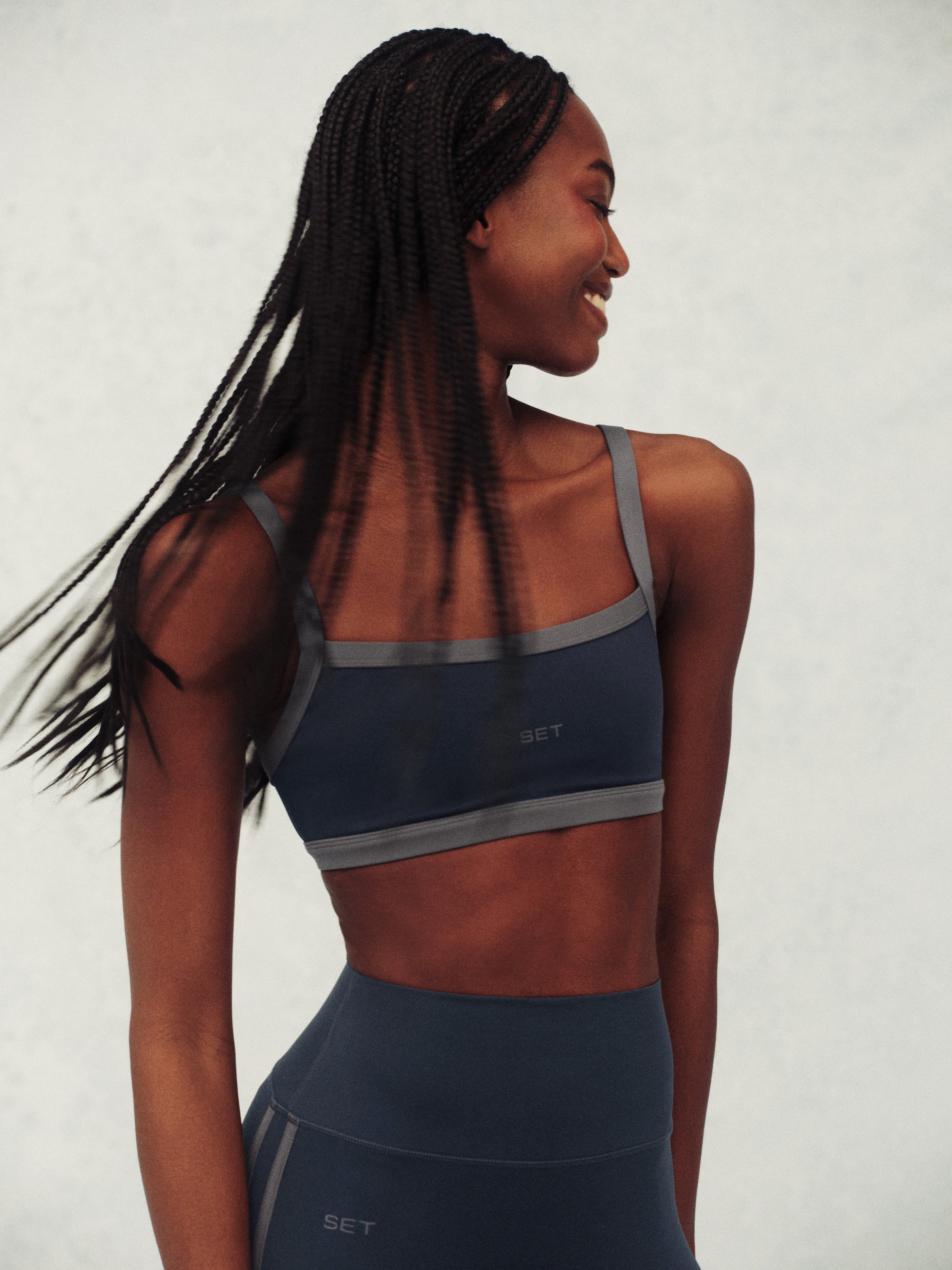 Woman wearing a blue sports bra and leggings with 'SET' branding on a plain background