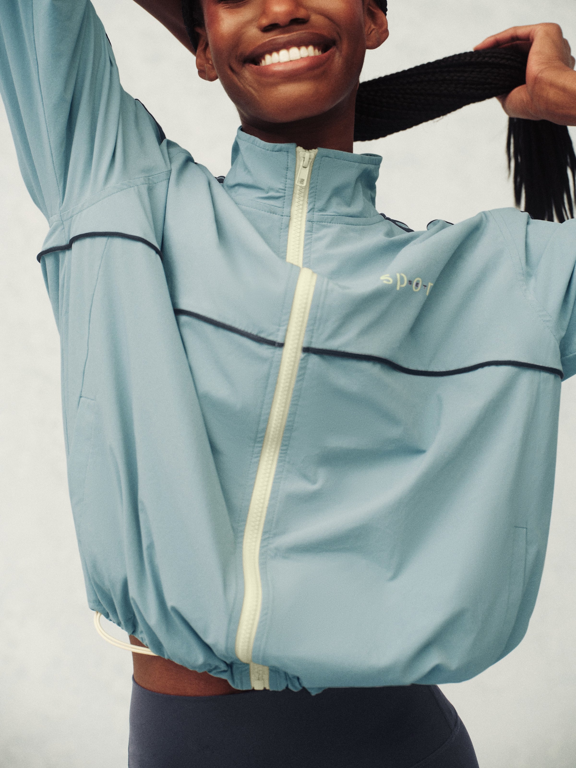 Woman wearing a light blue jacket with black stripes on a plain background