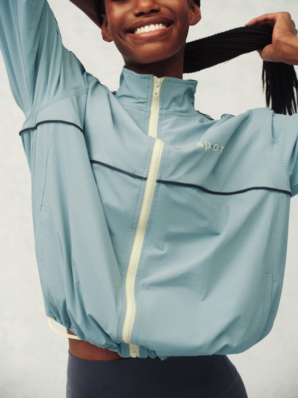 Woman wearing a light blue jacket with black stripes on a plain background