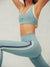 Person wearing a light blue sports bra and leggings with a white background