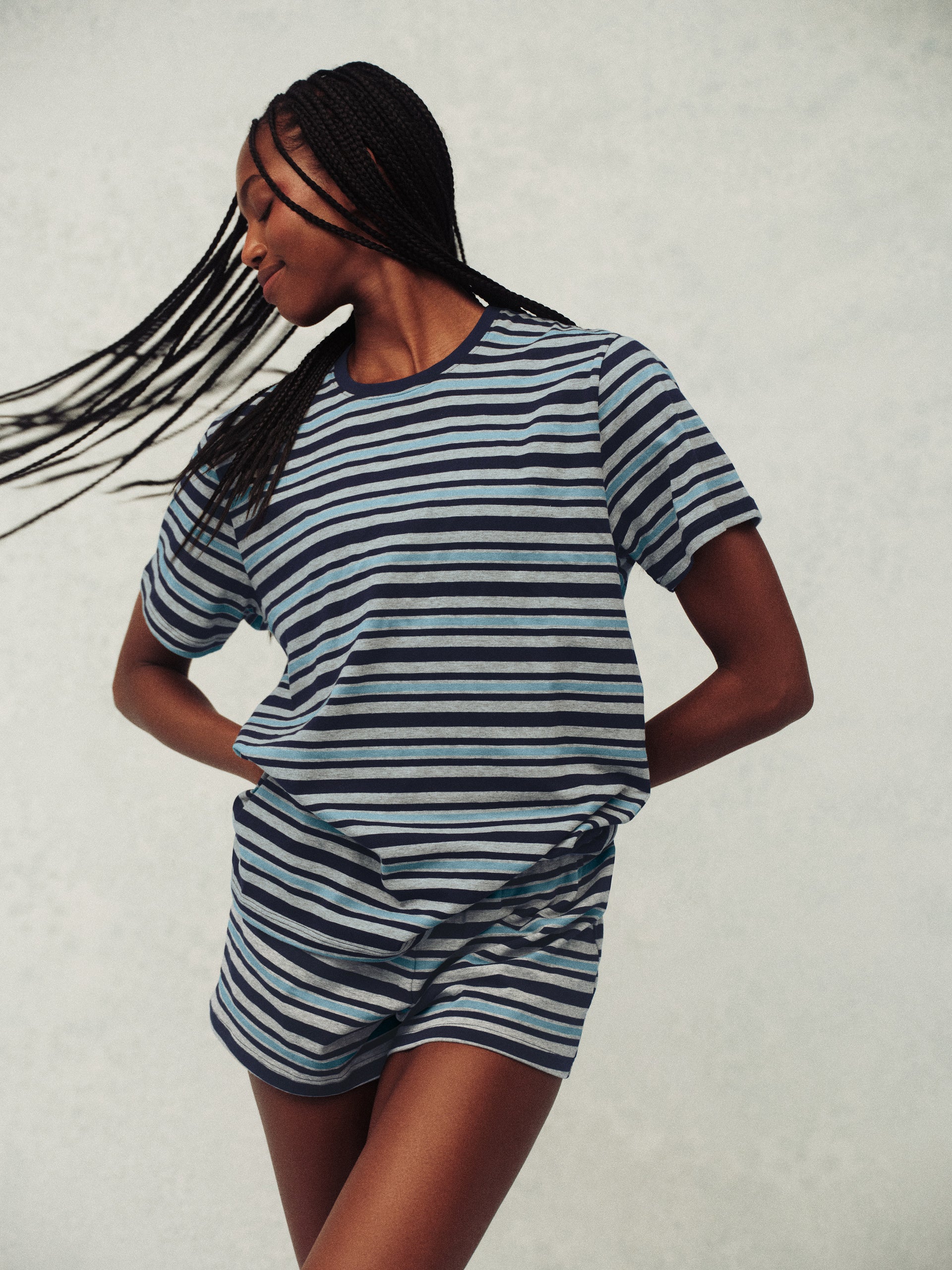 Woman wearing a blue and white striped outfit against a plain background