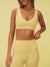 Woman wearing a yellow sports bra and leggings on a beige background