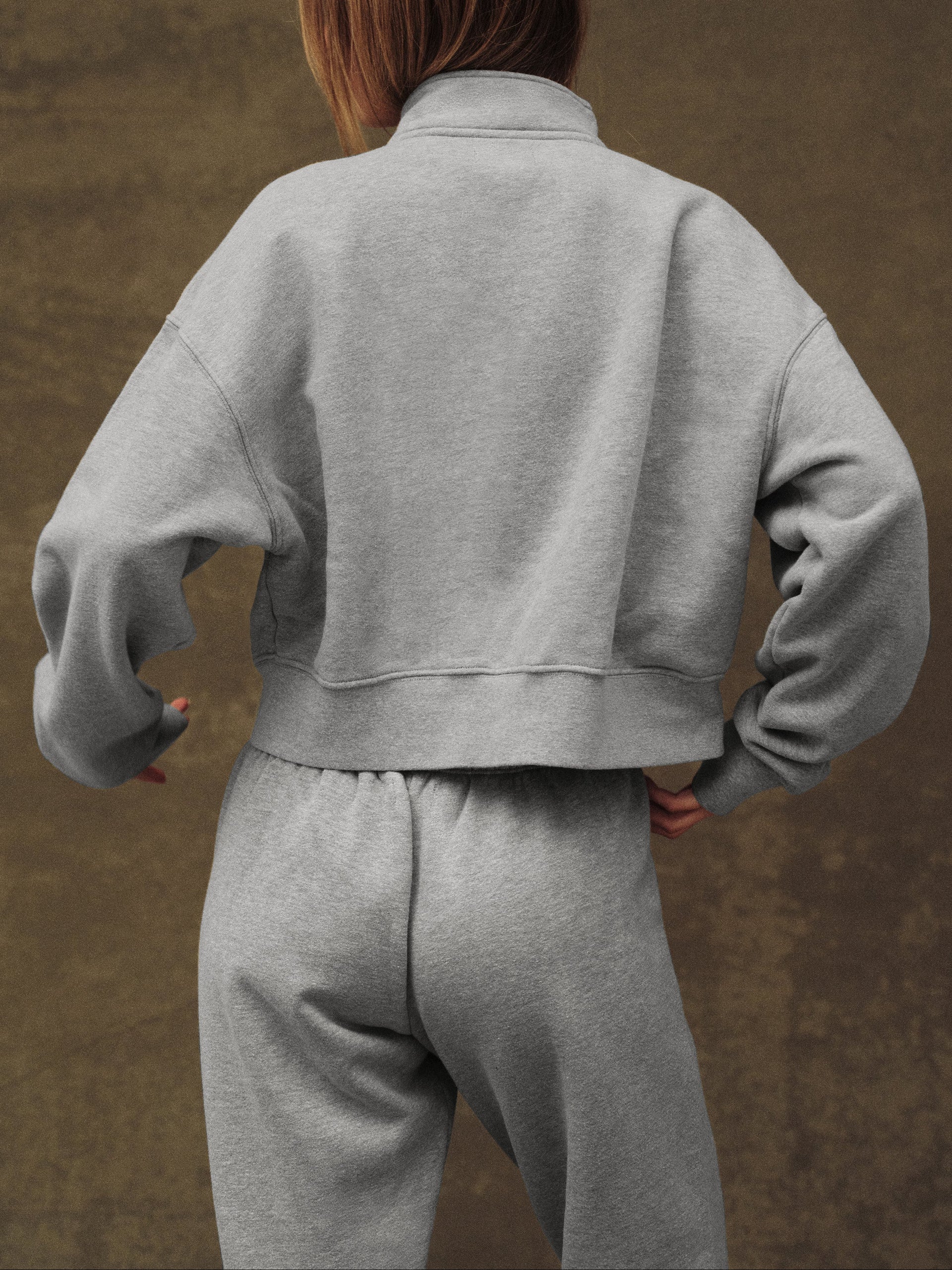 Person wearing a gray tracksuit against a brown background
