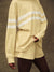 Beige oversized sweatshirt with reflective stripes worn by a person on a brown background