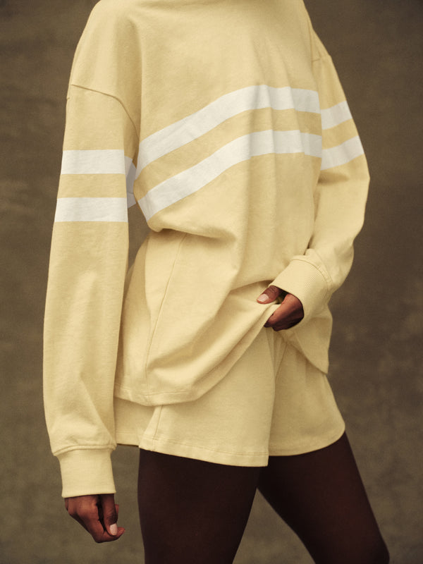 Beige oversized sweatshirt with reflective stripes worn by a person on a brown background