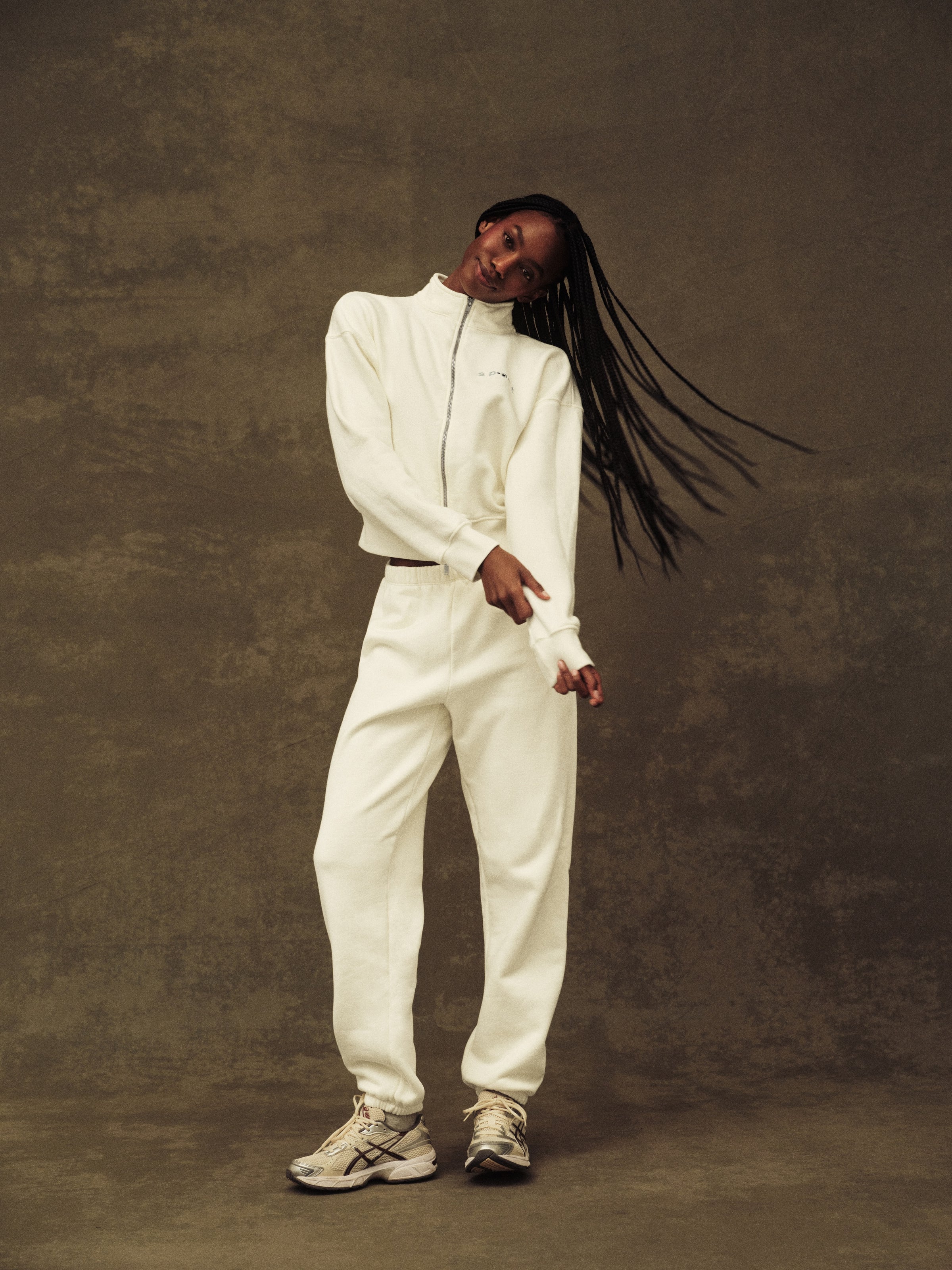 Person wearing a white outfit against a brown background