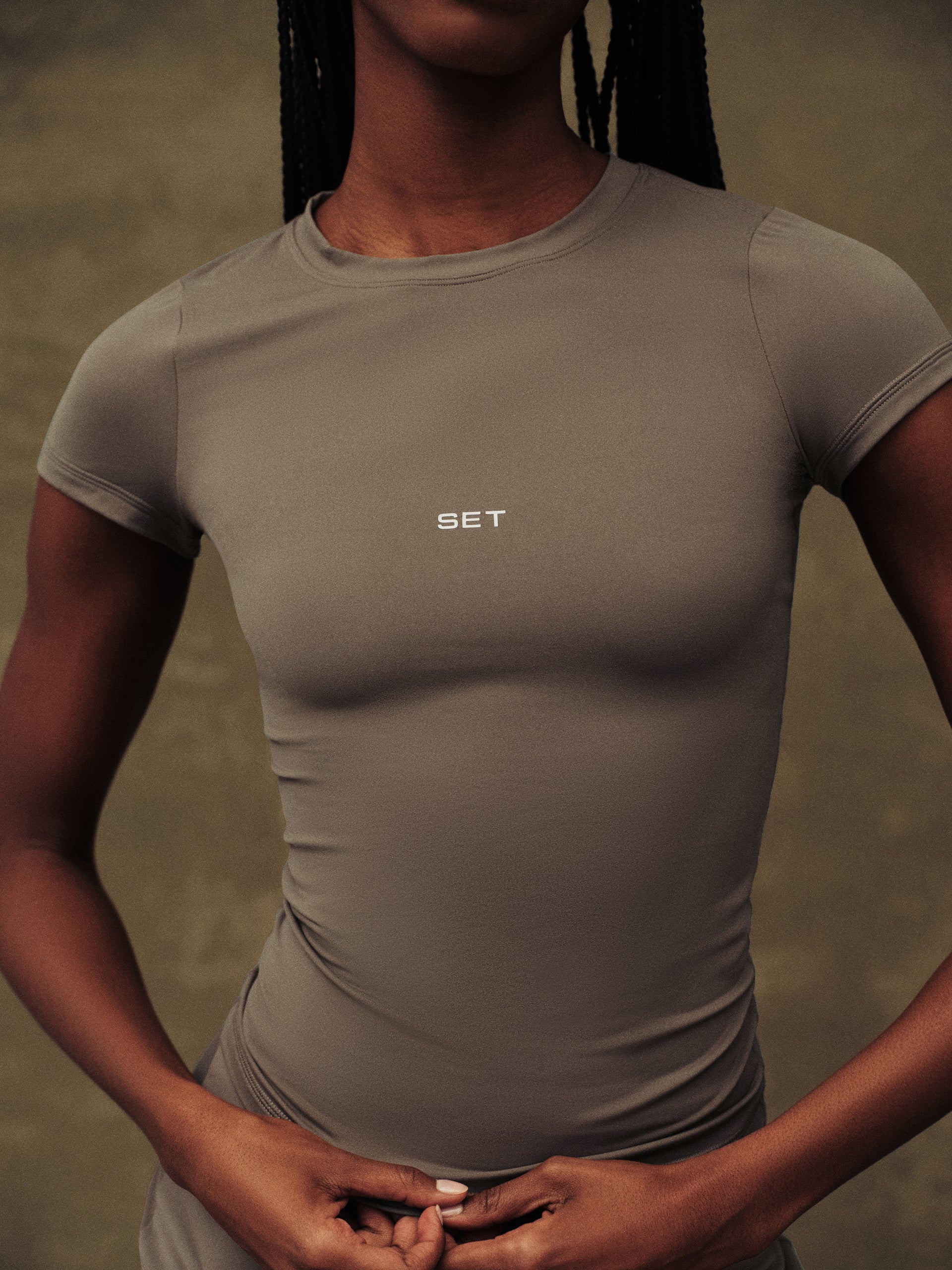 Person wearing a beige athletic shirt with 'SET' logo on a neutral background