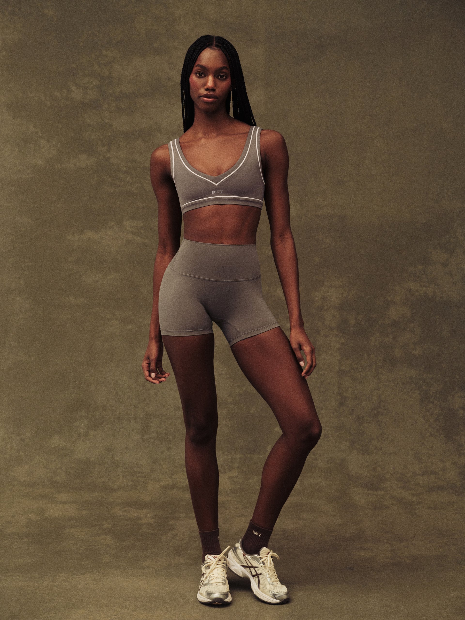Woman wearing a sports bra and shorts set on a textured brown background