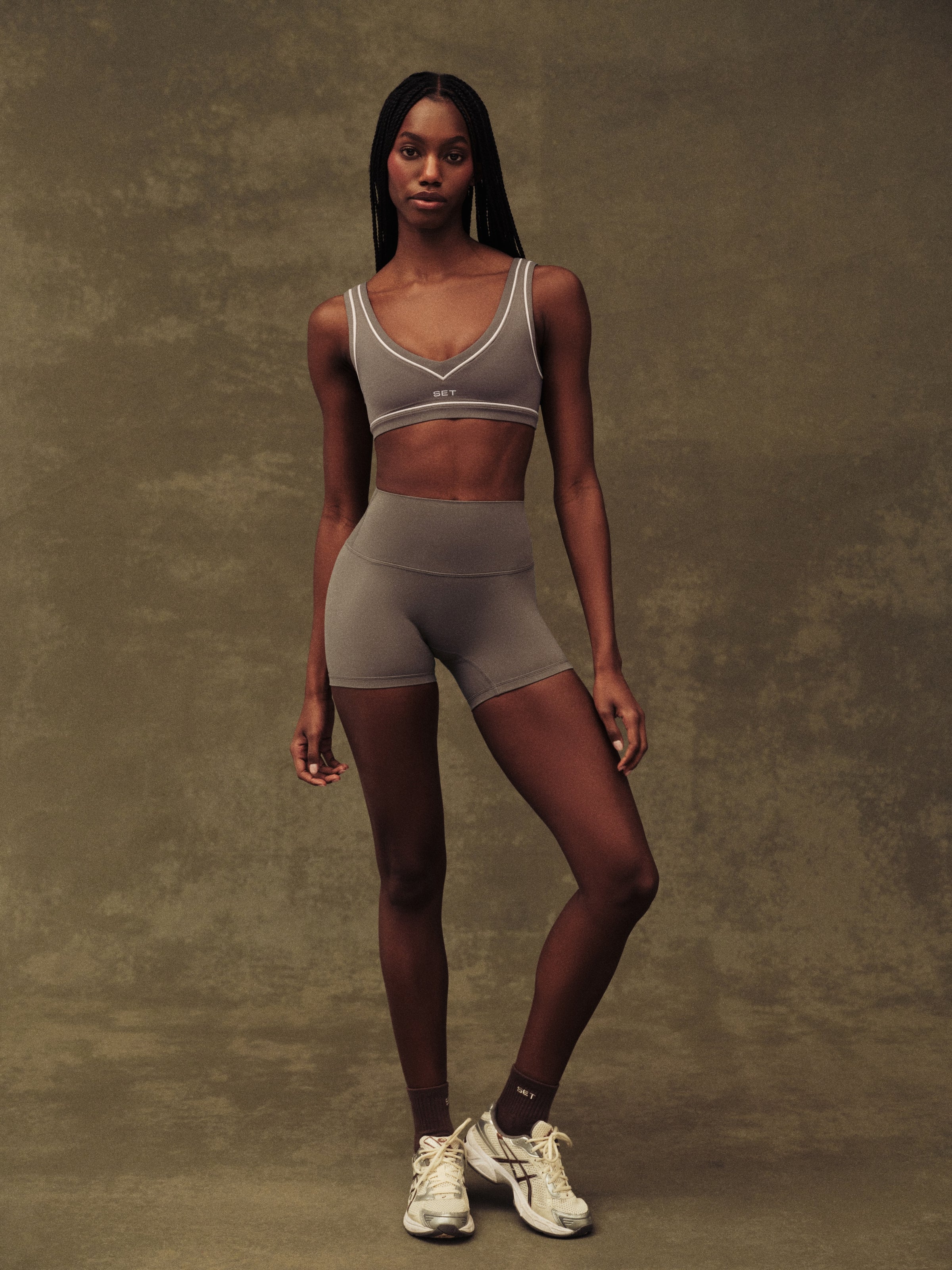 Woman wearing a sports bra and shorts set on a textured brown background