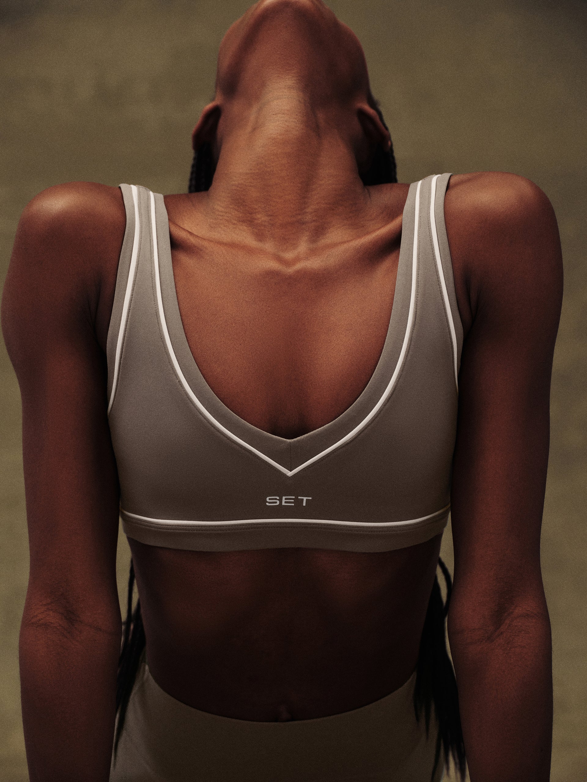 Person wearing a gray sports bra with 'SET' branding on a neutral background