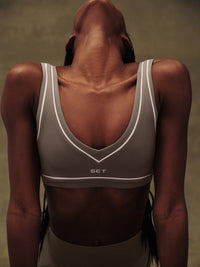 Person wearing a gray sports bra with 'SET' branding on a neutral background