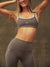 Woman wearing a gray sports bra and leggings with 'SET' branding against a brown background