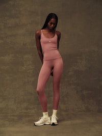 Person wearing a pink athletic outfit against a textured brown background