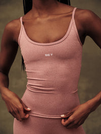 Person wearing a pink tank top with 'SET' logo on a blurred background