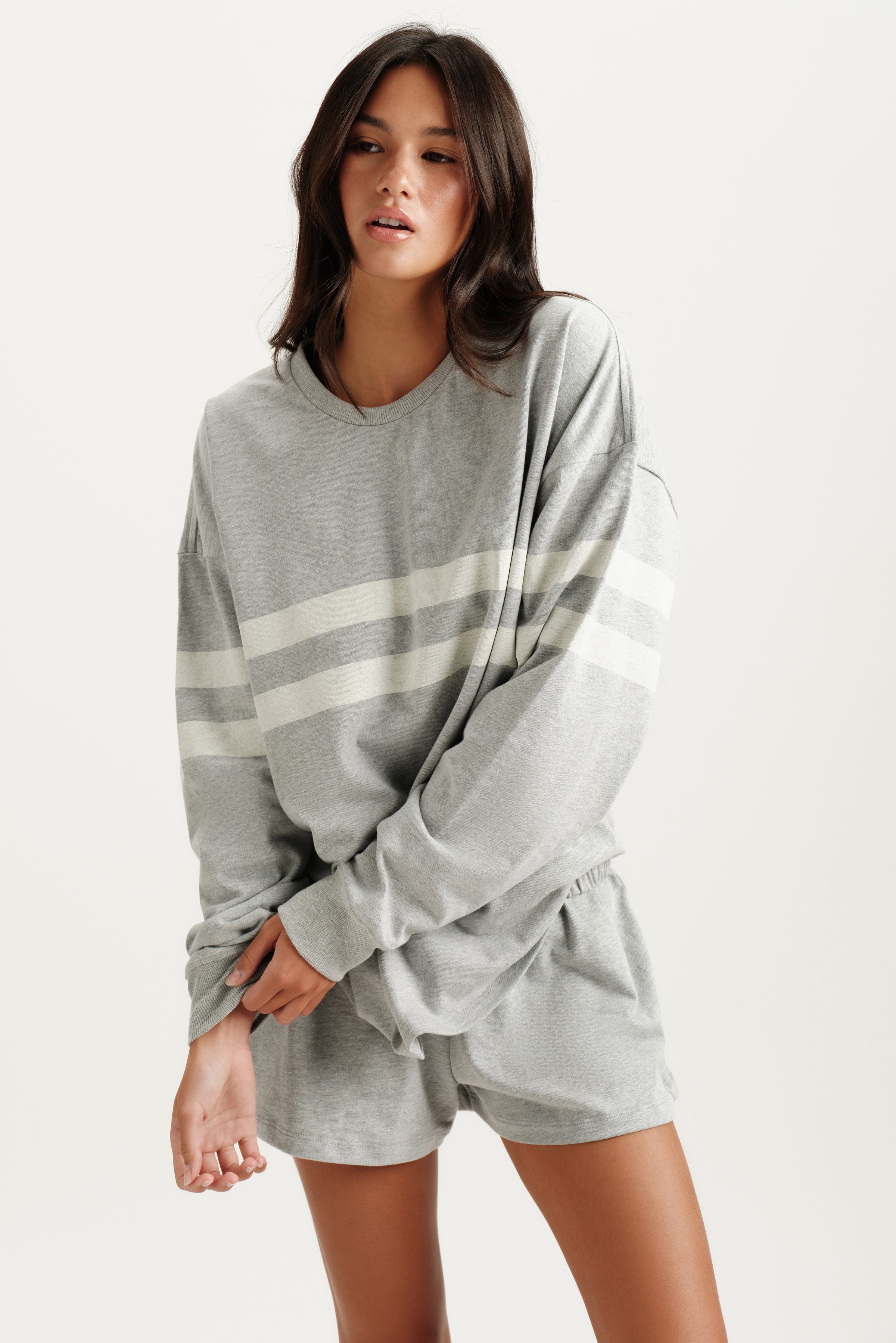 Woman wearing a gray oversized sweatshirt and shorts set on a white background 