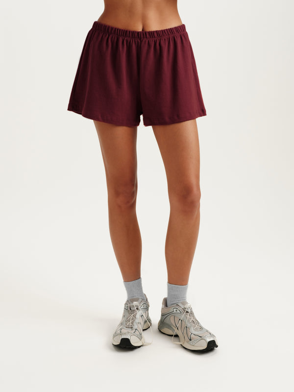 Maroon shorts worn by a person on a white background 