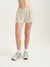 Person wearing cream shorts on a plain background
