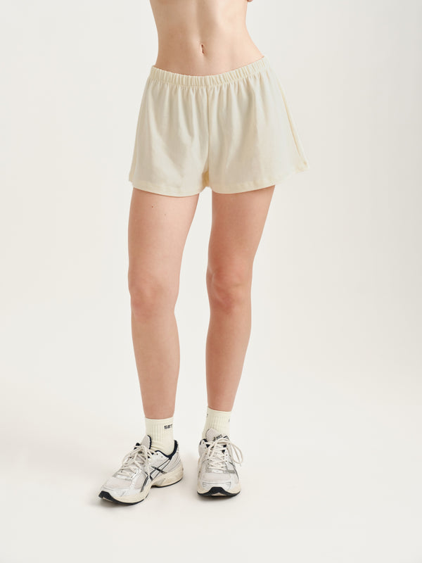 Person wearing cream shorts on a plain background