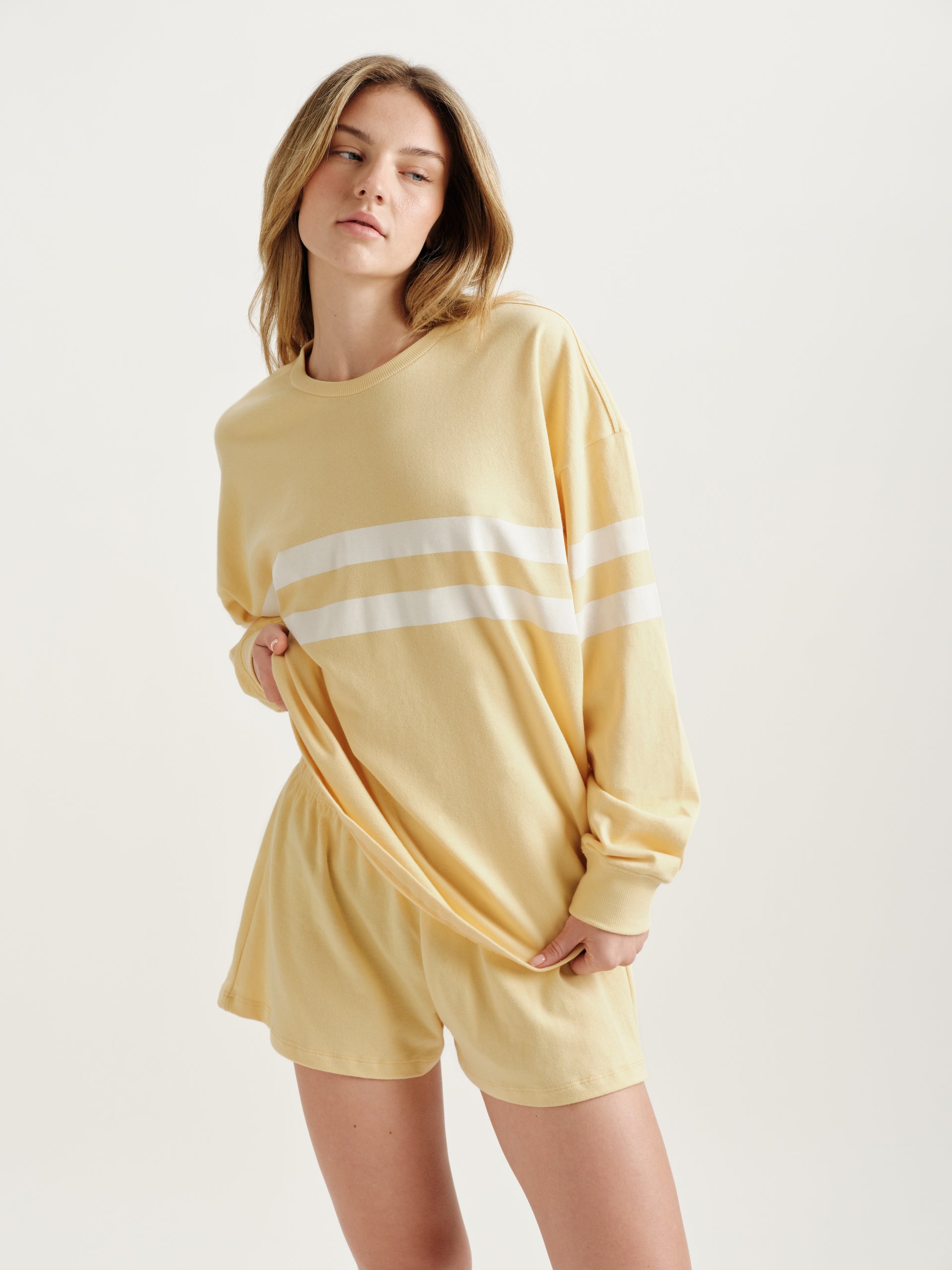 Woman wearing a yellow loungewear set with a white stripe on a light background <model-info>Alyssa wears a size S and is 5’9, 23” waist, 32B bust.</model-info>
