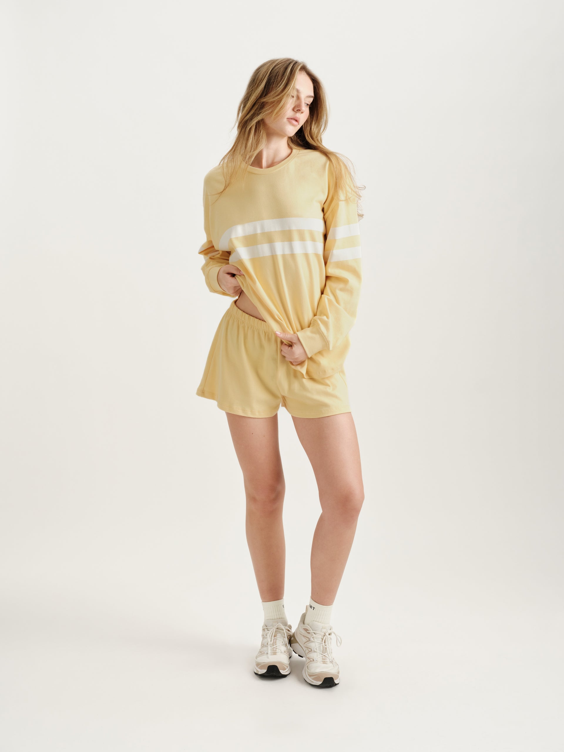 Woman wearing a yellow outfit with white stripes on a white background 