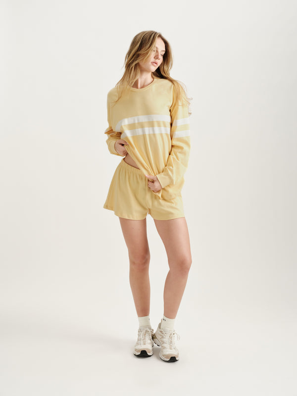 Woman wearing a yellow outfit with white stripes on a white background 