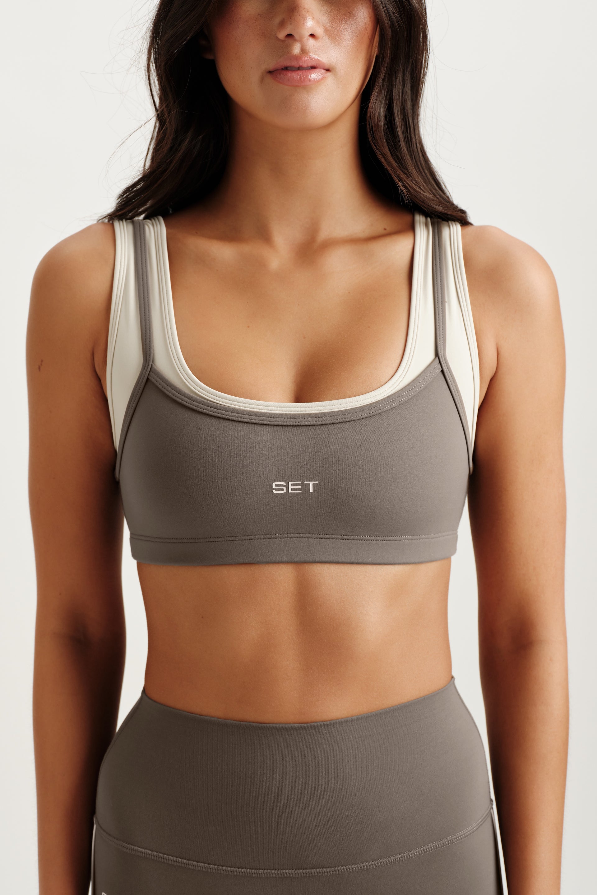 Woman wearing a gray sports bra with 'SET' branding on a white background