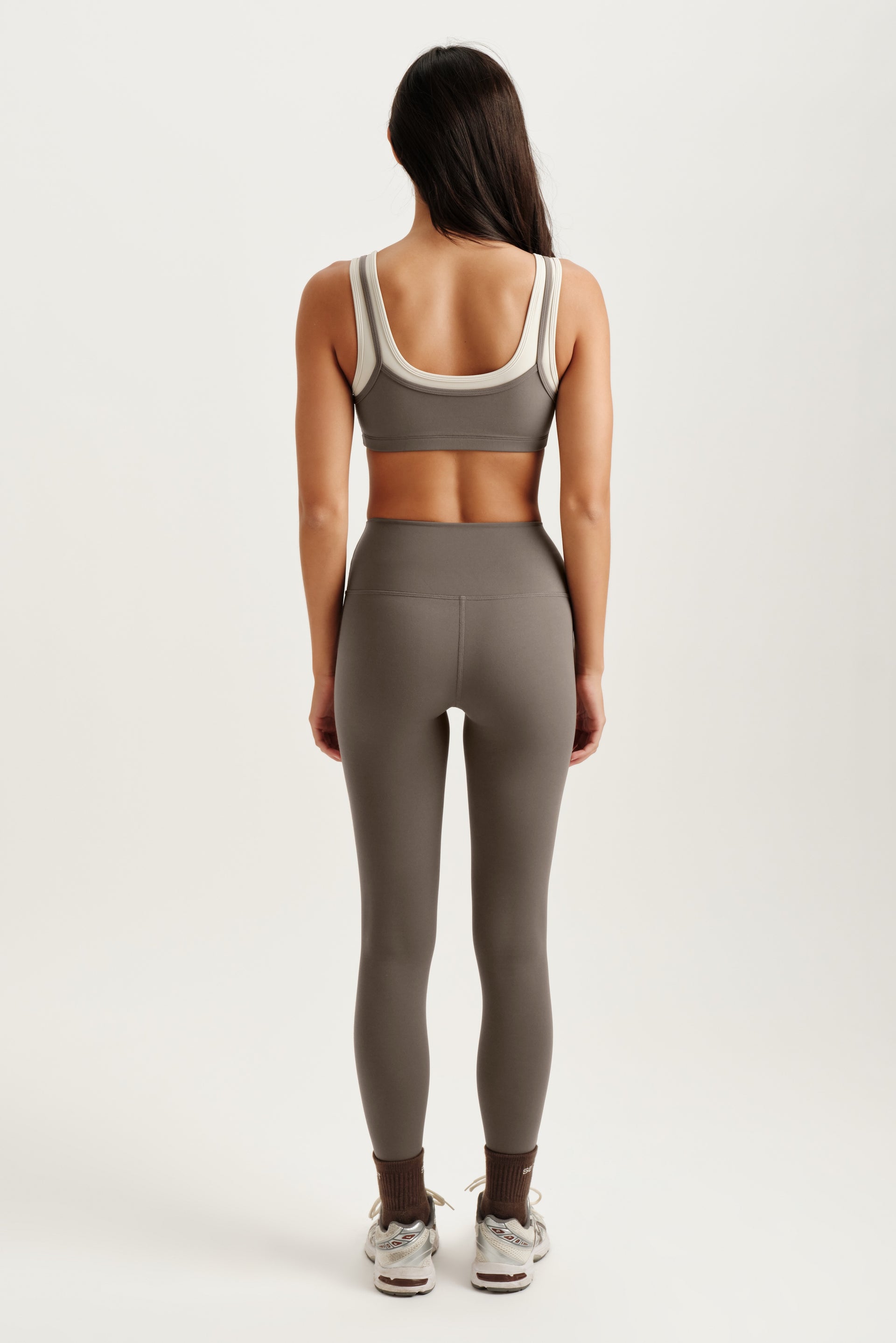 Person wearing a gray sports bra and leggings set on a white background