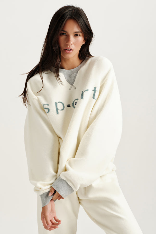 Woman wearing a cream-colored lounge set with 'Sport' text on a white background 