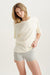 Woman wearing a white oversized shirt and gray shorts on a white background <model-info>Alyssa wears a size S and is 5’9, 23” waist, 32B bust.</model-info>