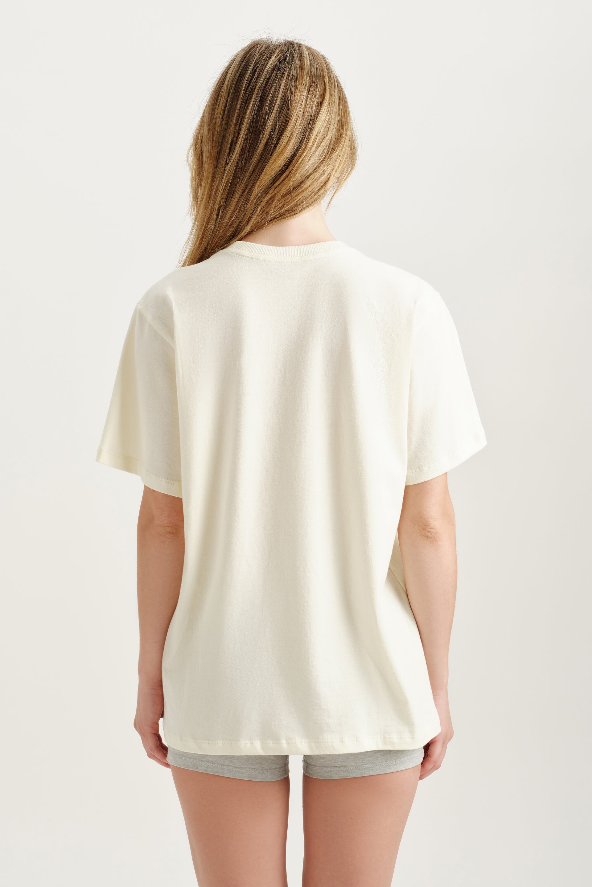 Person wearing a plain white t-shirt on a light background