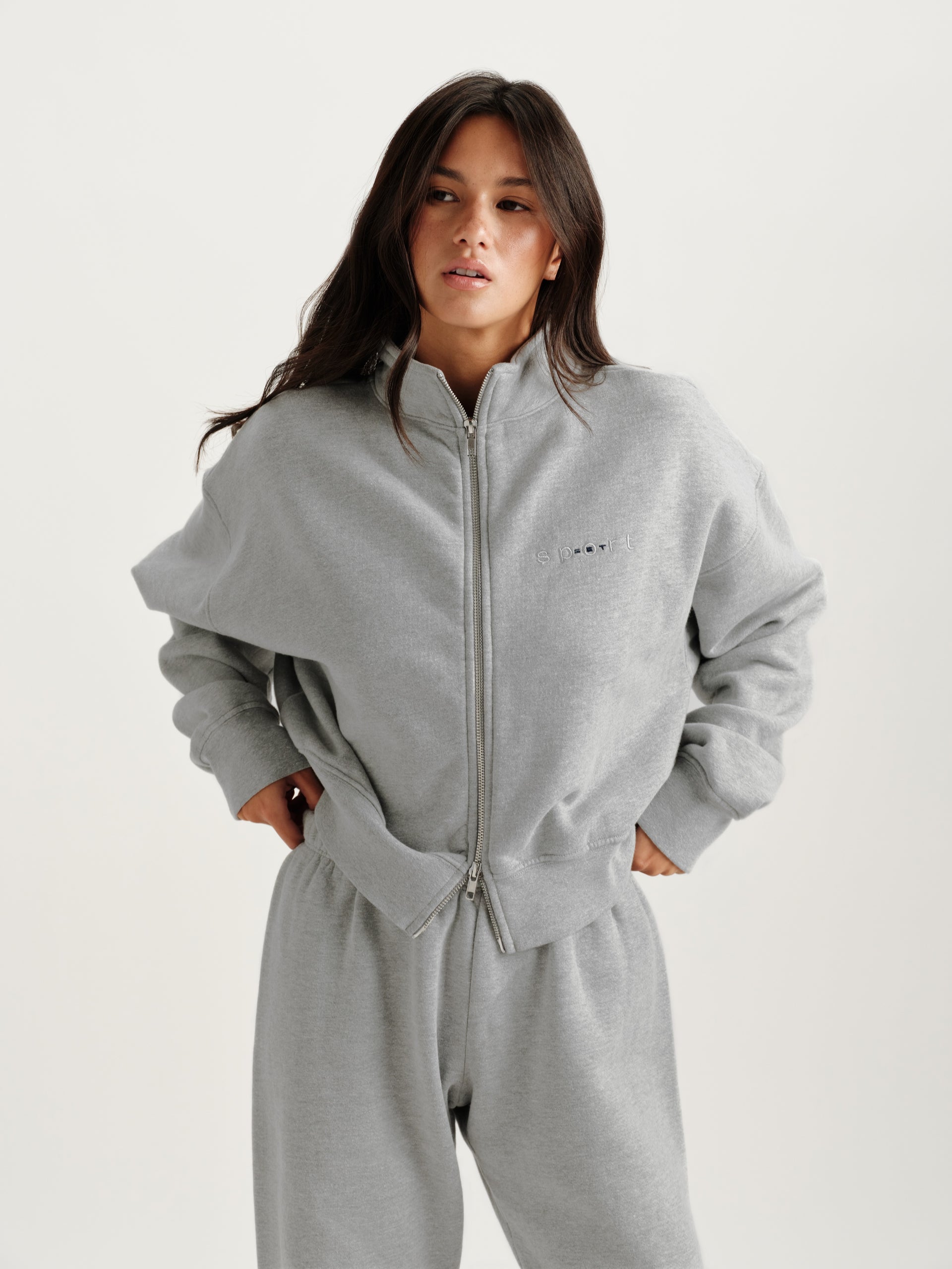 Person wearing a gray zip-up hoodie and pants on a white background <model-info>Jelene wears a size S and is 5’7”, 23” waist, 32AB bust.</model-info>