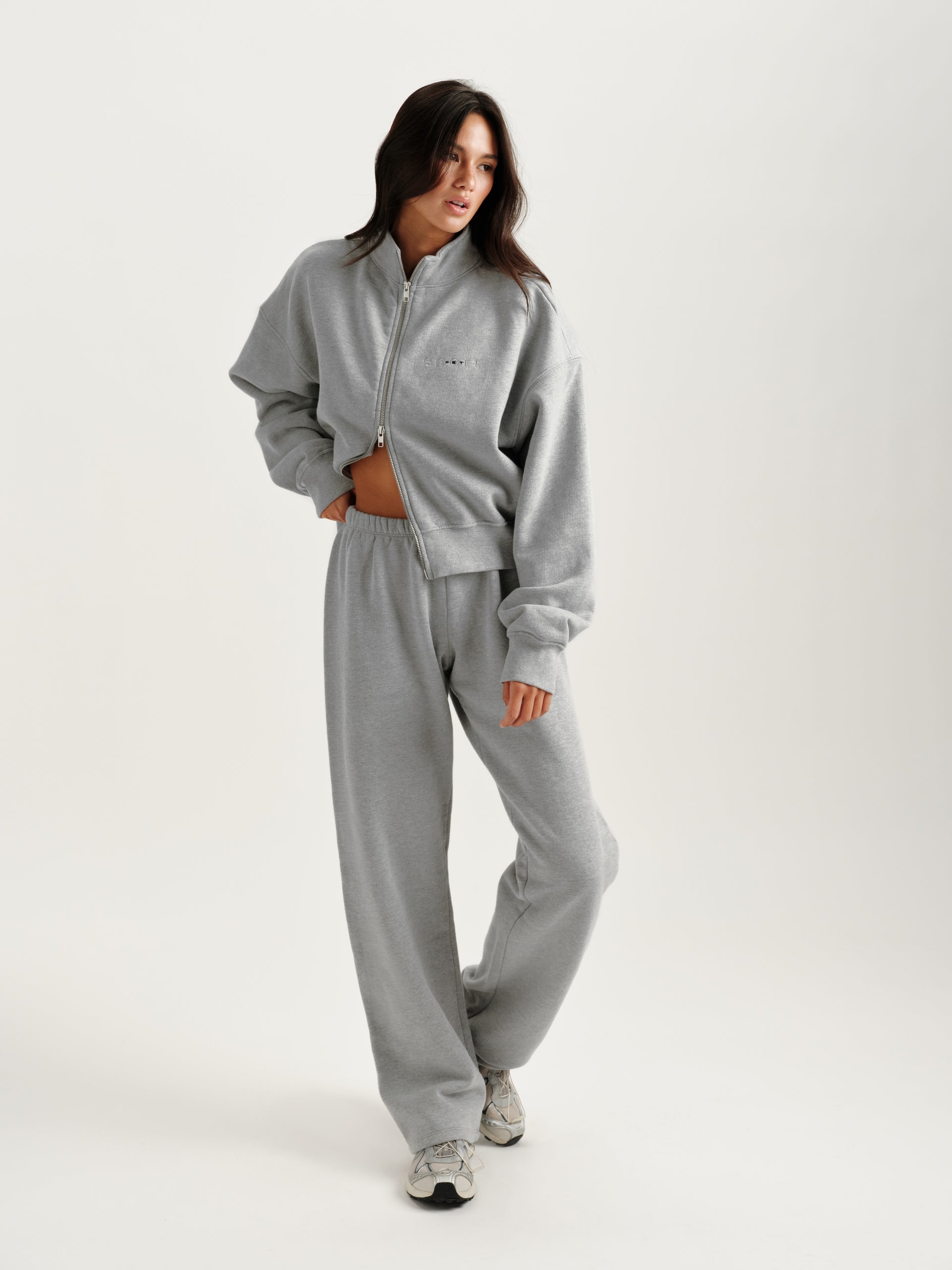 Woman wearing a gray tracksuit on a white background