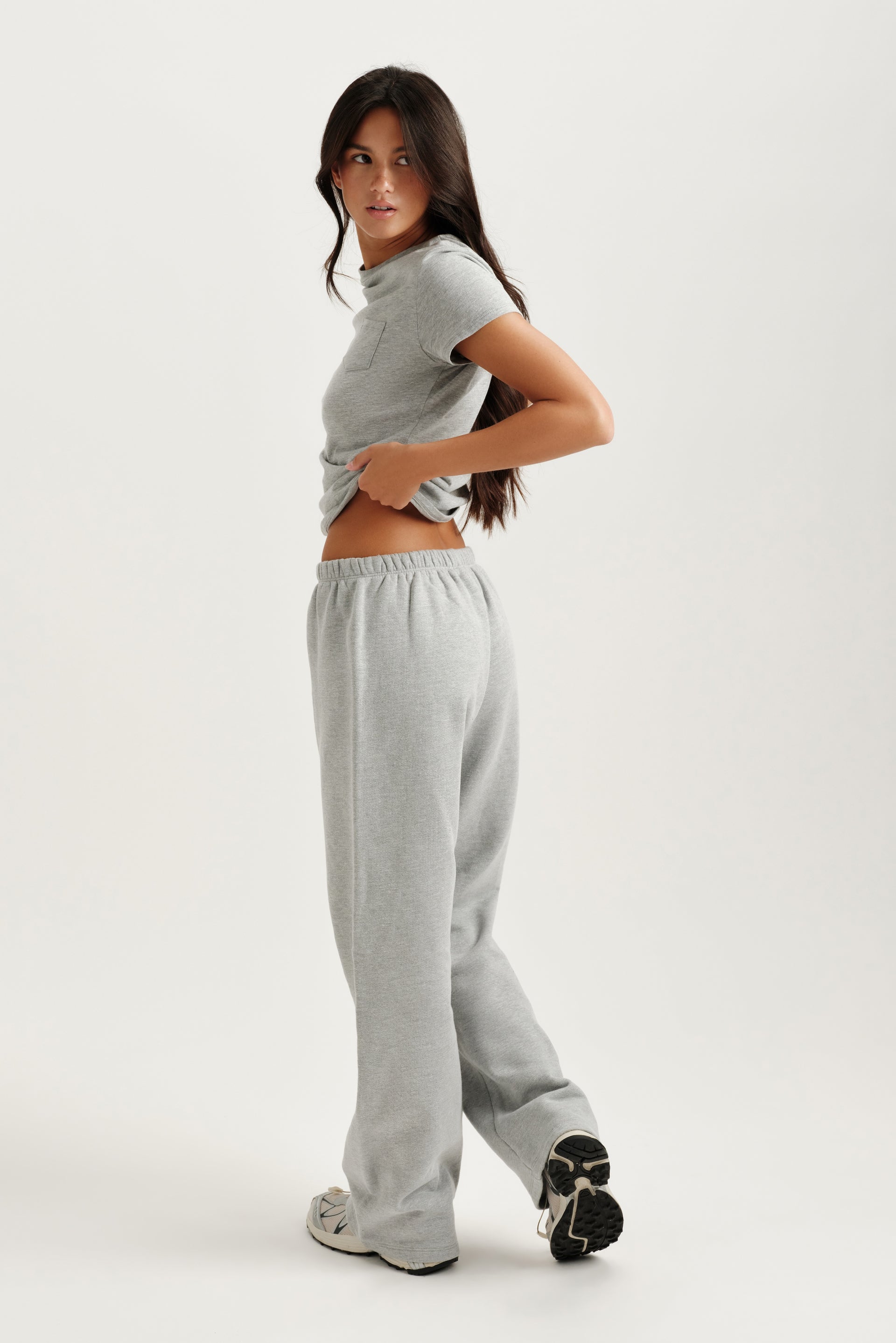 Woman wearing a gray t-shirt and sweatpants on a white background