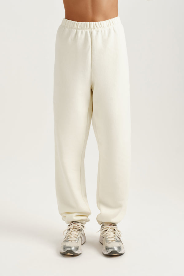 White sweatpants worn by a person on a white background 