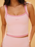 Pink tank top with thin straps on a person against a yellow background