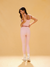 Woman wearing a pink tank top and leggings against a beige background