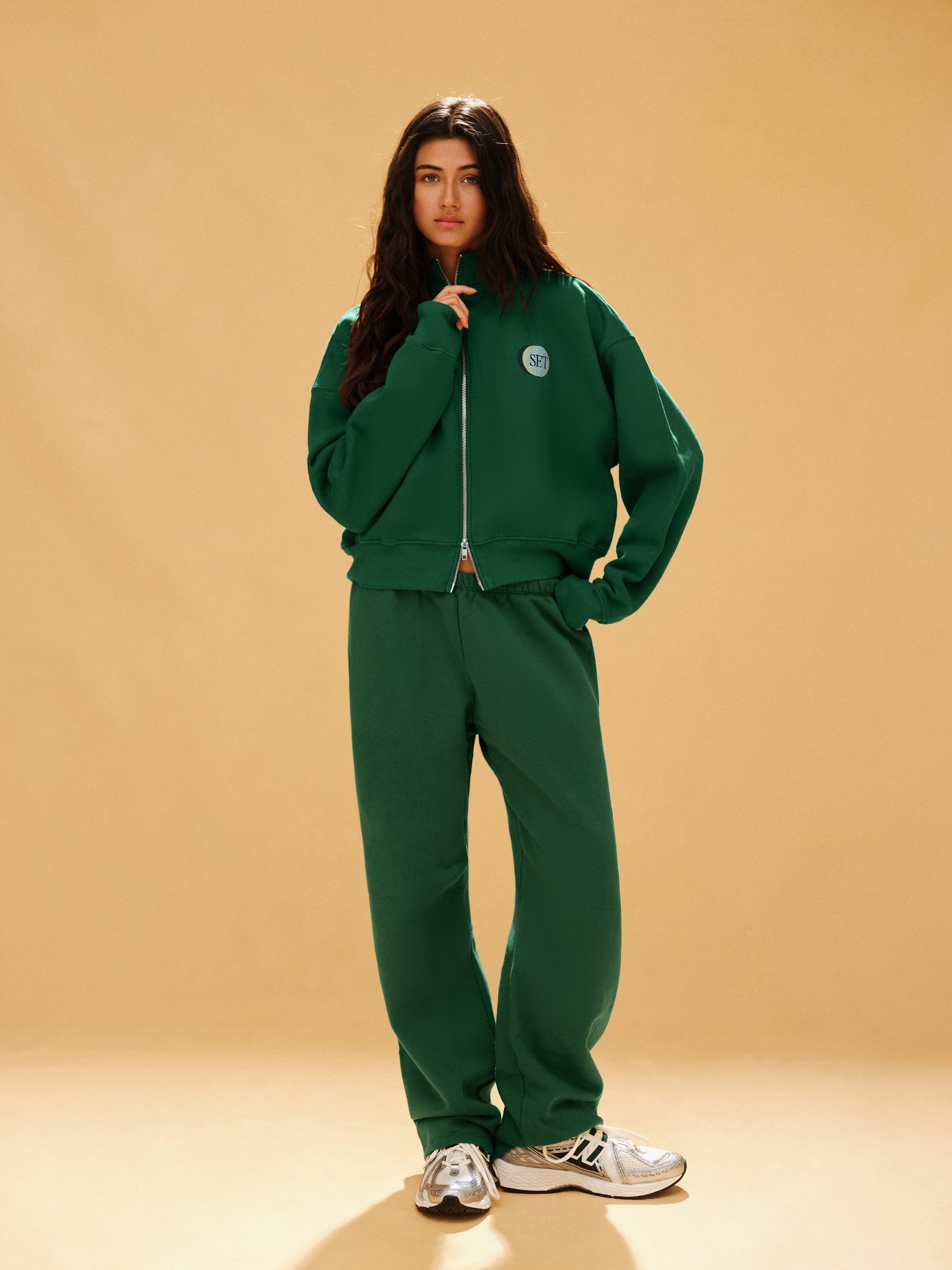 Person wearing a green tracksuit on a beige background