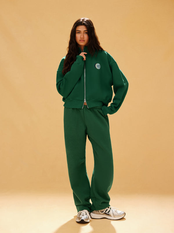 Person wearing a green tracksuit on a beige background