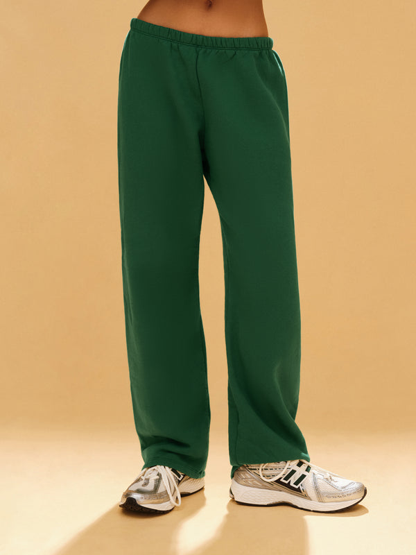 Green sweatpants worn by a person on a beige background